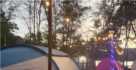 Tenda dan lampu gantung saat senja menjelang malam di area camping Injros View