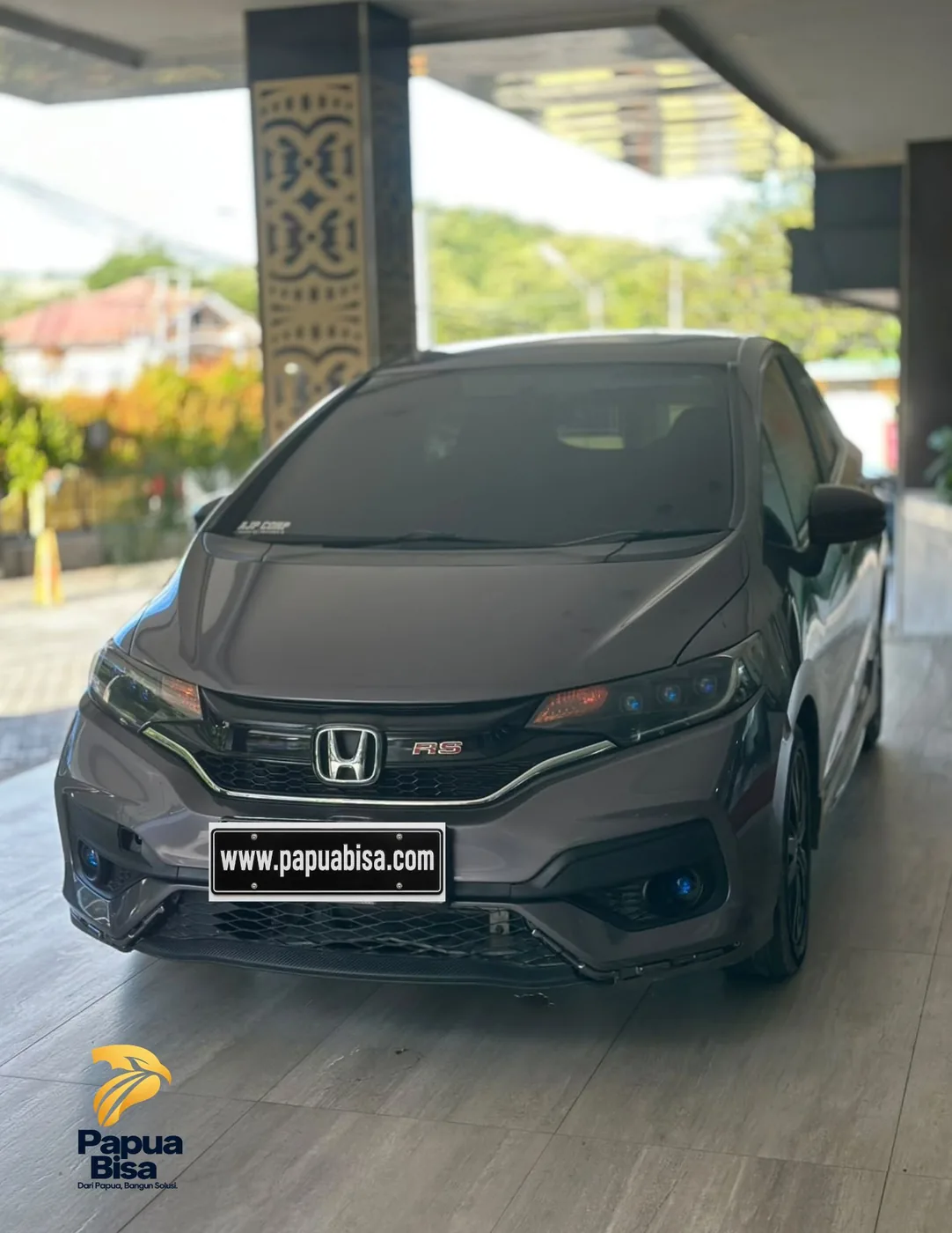 Unit Honda abu-abu di area drop-off berkanopi